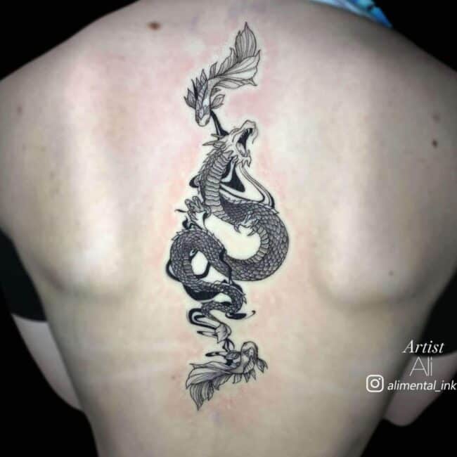 Ali Tattoo Artist Fine Line Black and Grey Detailed Roaring Dragon Betta Fish At The Top and Bottom With Flowing Black Shadow in The Background Back Spine Tattoo