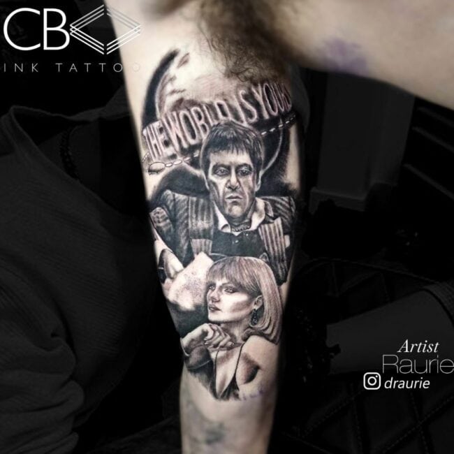 Raurie Tattoo Artist Realism Black and Grey Tony Montana Portrait and His Blonde Love Portrait with Writing The World Is Yours in the Background Arm Tattoo
