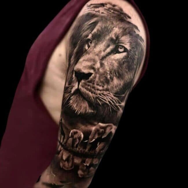 Realism Focused Lion With Elephants And Giraffe Below Representing Prey Shoulder Tattoo