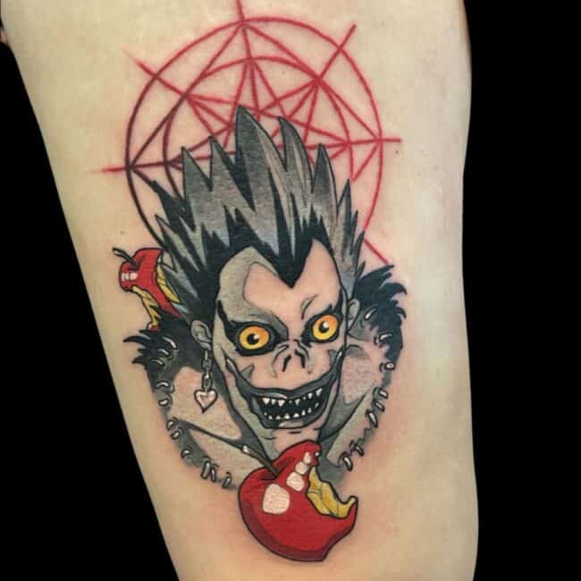Rhys Tattoo Artist Anime Cartoon Colour Death Note Grinning Ryuk Portrait Two Half Eaten Apples Red Symbol In The Background Arm Tattoo