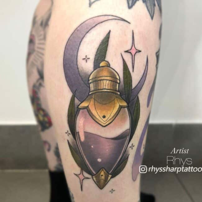 Rhys Tattoo Artist Neo Traditional Colour Small Potion Gold Top and Bottom Purple Liquid with Purple Stars and Moon in the Background Ankle Tattoo