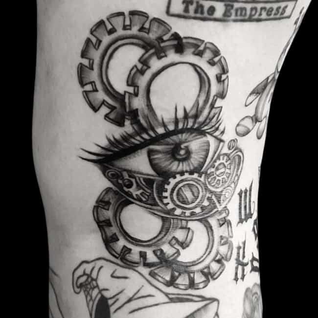 Riana Tattoo Artist Black and Grey Fine Line Realism Blackwork Steampunk Eye Gear Wheels Lashes Detailed Pupil Arm Tattoo