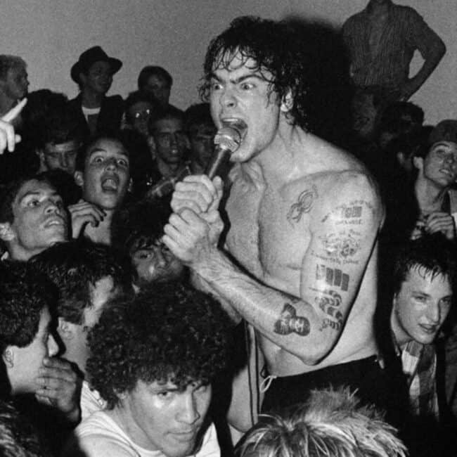 Shirtless Henry Rollins Singing Loudly in The Microphone Showing off His Chest and Arm Tattoos Black and White Photo