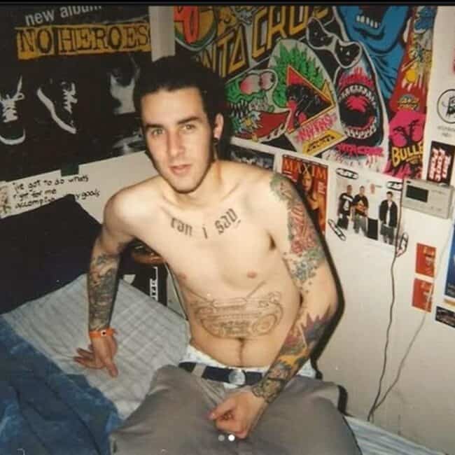 Shirtless Travis Barker Showing off His Arms Tattoos and Chest and Belly Tattoos Sitting on Bed Photo