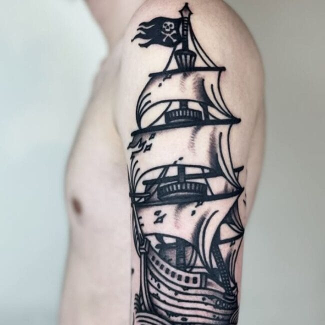 Black and Grey Traditional Pirate Ship Sailing Through Sails with Skull Pirate Flag Crows Nest Hull Jib Sail Mast Sharp Bowsprit Arm Shoulder Tattoo
