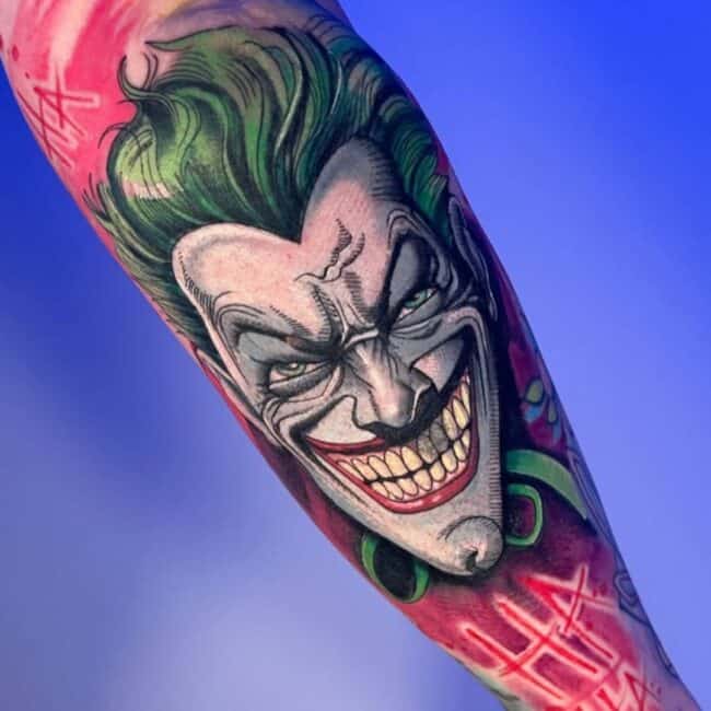 Colour Cartoon Comic Book Joker Distinctive Smile Detailed Facial Features With Abstract Red Background with Ha Ha Lettering Forearm Tattoo