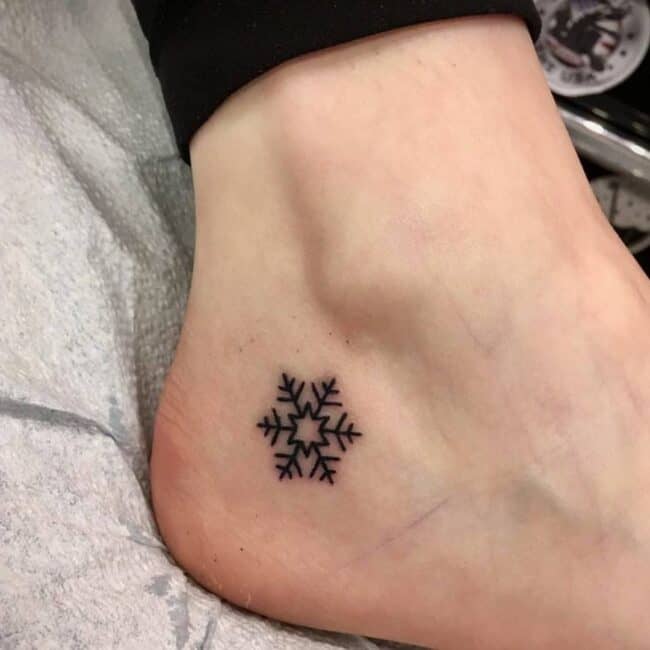 Minimalist Black and Grey Fine Line Snowflake Tattoo on the Foot Designed with Delicate and Symmetrical Patterns For An Elegant Look Leg Foot Tattoo
