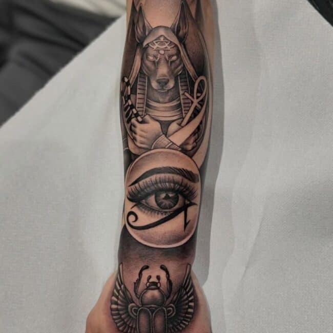 Black and Grey Realism Blackwork Anubis Jackals Head Eye of Horus Ancient Egyptian Symbol Bold Ankh Shaped Cross with Loop Scarab Beetle Pyramid Forearm Hand Tattoo