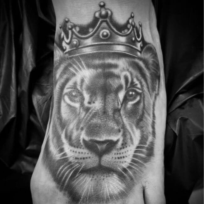 Black and Grey Realism Detailed Eyes Whiskers Mouth Nose Lion Mane Crown Foot Tattoo