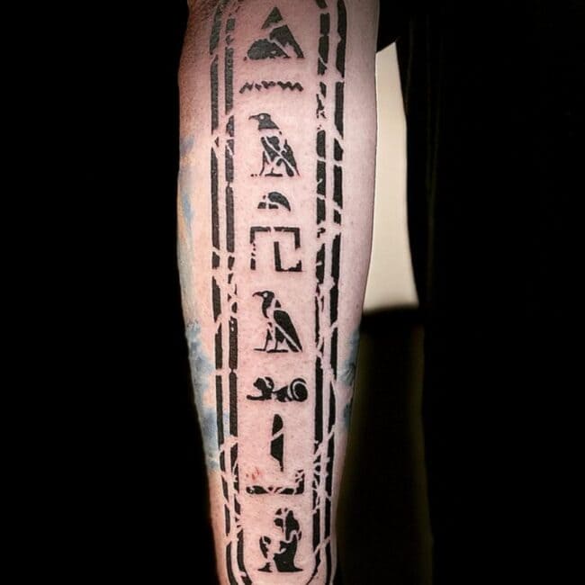 Blackwork Black and Grey Hieroglyph Ancient Egyptian Symbol Pyramid Falcon Bird Depicts Pyramids Bold Cracked Border Arm Forearm Tattoo