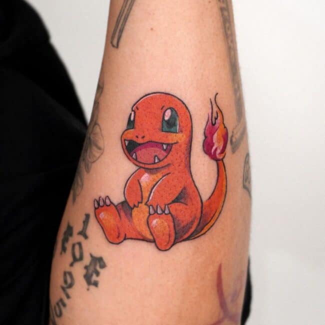 Colour Anime Cartoon Charmander Sitting Big Smile Sharp Teeth Nails Green Eyes Round Face Flame Tail Forearm Tattoo