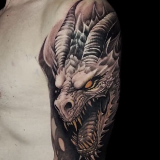 Sunny Tattoo Artist Black and Grey Blackwork Realism Detailed Dragon Head Scales Sharp Skin Teeth Horns Fierce Yellow Dark Eye Upper Arm Tattoo