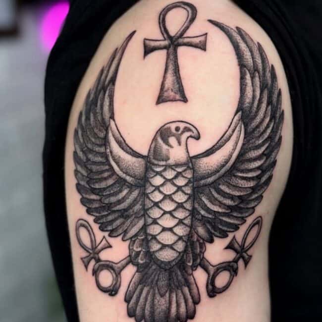 Traditional Black and Grey Falcon Bird Ancient Egyptian Symbol Bold Ankh Shaped Cross Loop Detailed Wings Beak Eye Tail Upper Shoulder Arm Tattoo