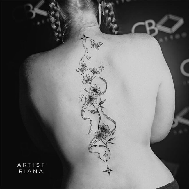 Riana Tattoo Artist Black and Grey Fine Lines Vertical Flower Bloom Butterfly Leaves Wave Dots Stem Vines Diamond Elements Spine Back Tattoo